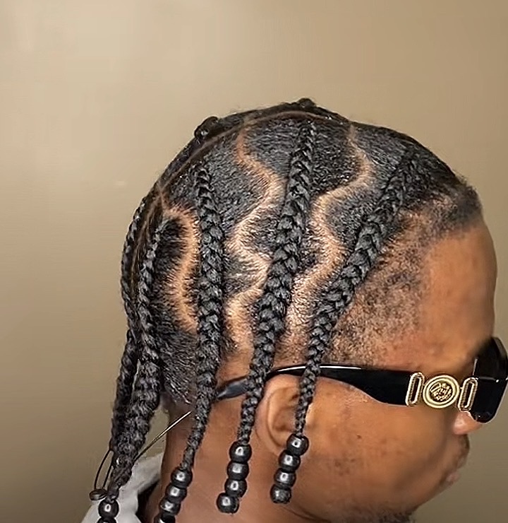 Men's freestyle braid design with curved partings and beaded ends.